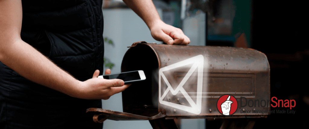 Image of person holding phone up to mail box with email graphic